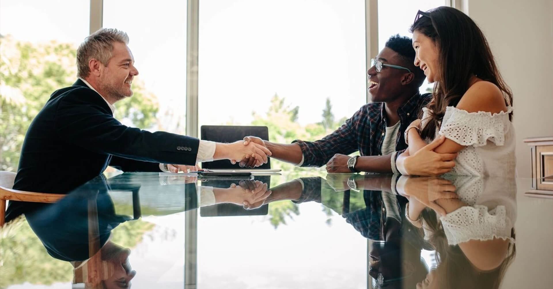 A group of people sitting around a table shaking hands.