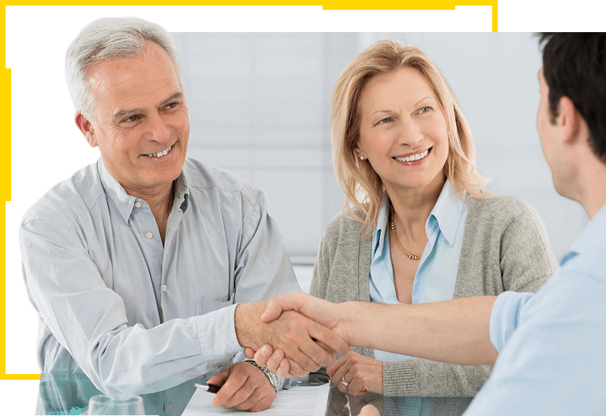 A man and woman shaking hands over a table.